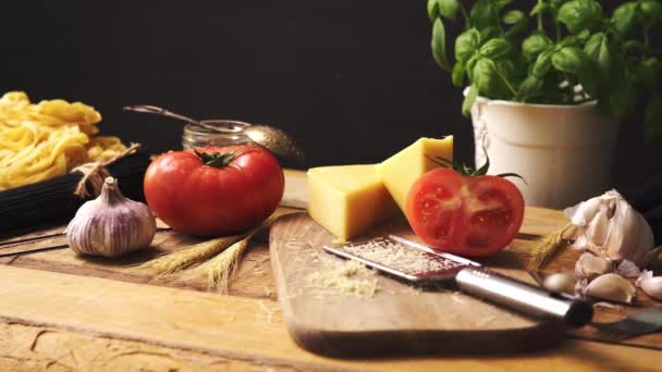 Queso rallado con albahaca fresca y espaguetis italianos sobre mesa de cocina de madera — Vídeo de stock