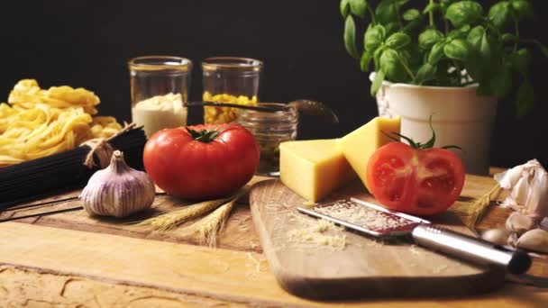 Geschredderter Käse mit frischem Basilikum und italienischen Spaghetti auf hölzernem Küchentisch — Stockvideo