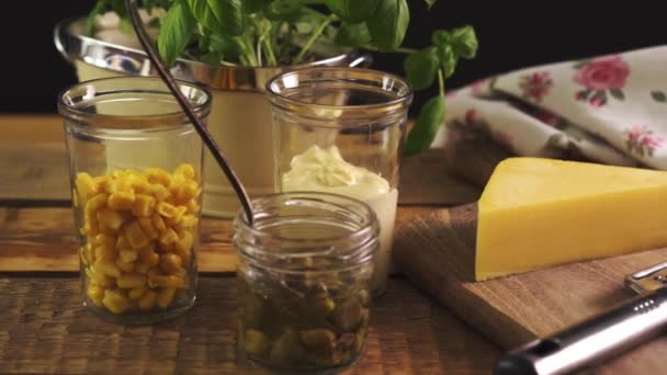 Fromage sur planche à découper et râpe au basilic frais sur table de cuisine en bois — Video