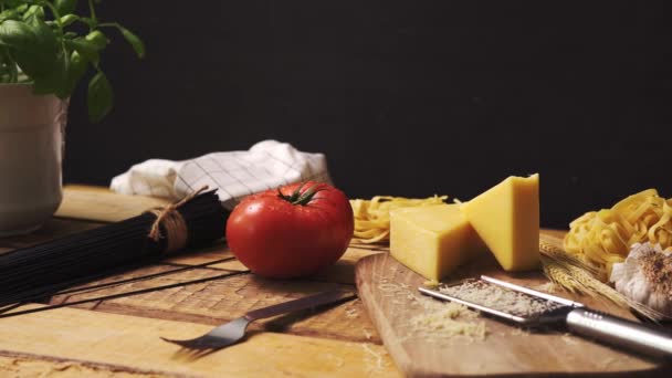 Queso rallado con albahaca fresca y espaguetis italianos sobre mesa de cocina de madera — Vídeos de Stock