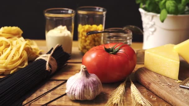 Geschredderter Käse mit frischem Basilikum und italienischen Spaghetti auf hölzernem Küchentisch — Stockvideo