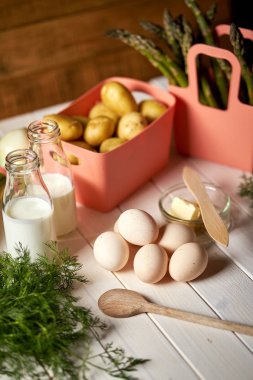 Beyaz mutfak masasında taze kuşkonus patates ve yumurta