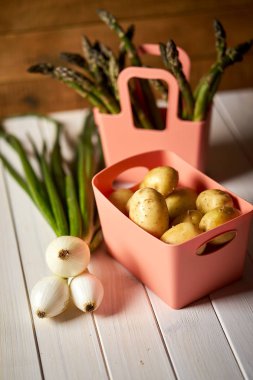 Beyaz mutfak masasında taze kuşkonus patates ve Frenk soğanı