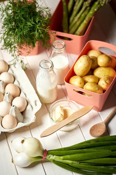 Beyaz mutfak masasında taze kuşkonus patates ve yumurta
