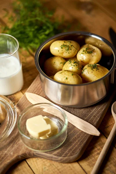 Patate giovani bollite in pentola con aneto e burro su tavola di legno — Foto Stock