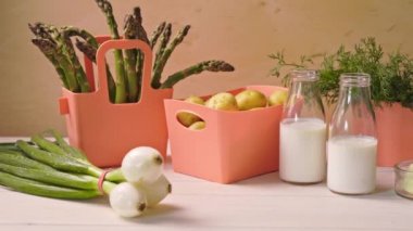 Mercan kaplarında bahar genç sebzeler ve masada süt ile şişeler