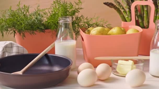 Весной молодые овощи с яйцами и с молоком и сковородкой на деревянном столе — стоковое видео