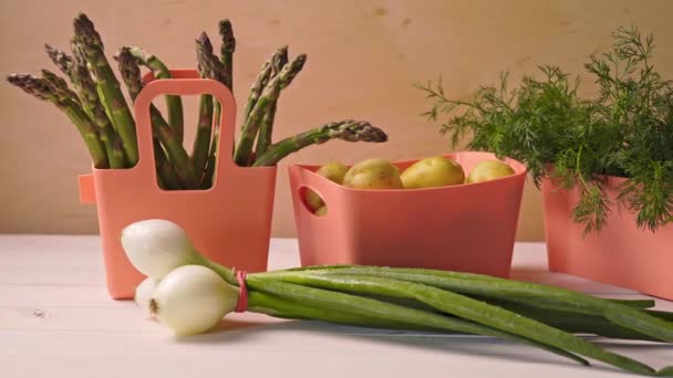 Verduras jóvenes de primavera en contenedores de coral sobre mesa de madera — Vídeo de stock