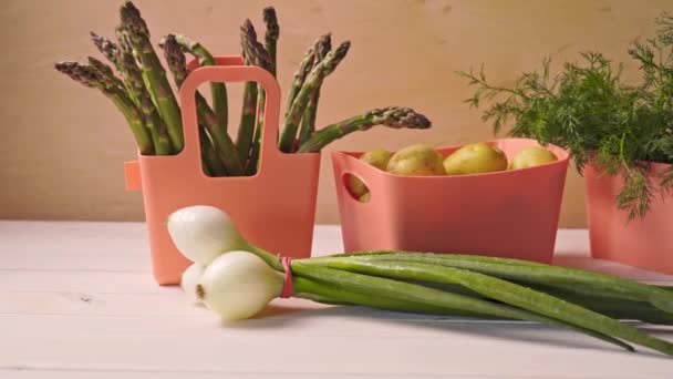 Primavera legumes jovens em recipientes de coral em mesa de madeira — Vídeo de Stock