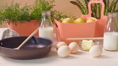 Yumurta ve süt ve ahşap masada tava ile Bahar genç sebzeler