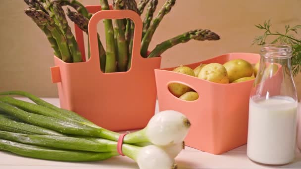 Spring young vegetables in coral containers and bottles with milk on table — Stock Video