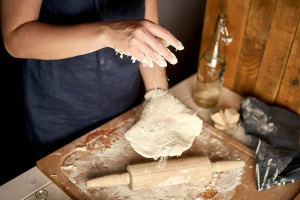 Kadın ahşap masada un ve haddeleme pin ile pasta tahtası üzerinde hamur hazırlar — Stok fotoğraf