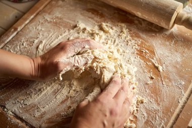 Kadın ahşap masada un ve haddeleme pin ile pasta tahtası üzerinde hamur hazırlar