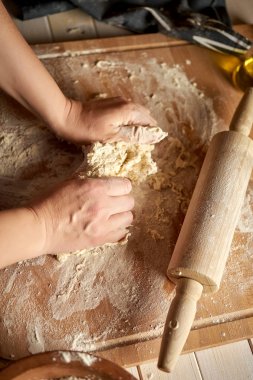 Kadın ahşap masada un ve haddeleme pin ile pasta tahtası üzerinde hamur hazırlar