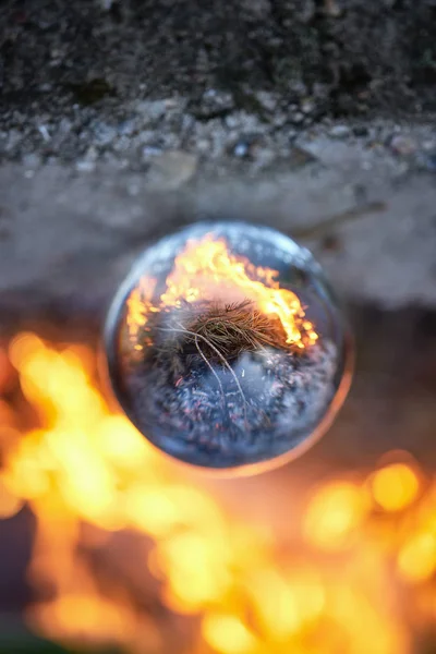 Vue à l'envers à travers la boule de verre sur le feu de camp brouillé dans la forêt — Photo