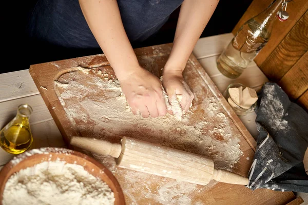 Kadın ahşap masada un ve haddeleme pin ile pasta tahtası üzerinde hamur hazırlar — Stok fotoğraf