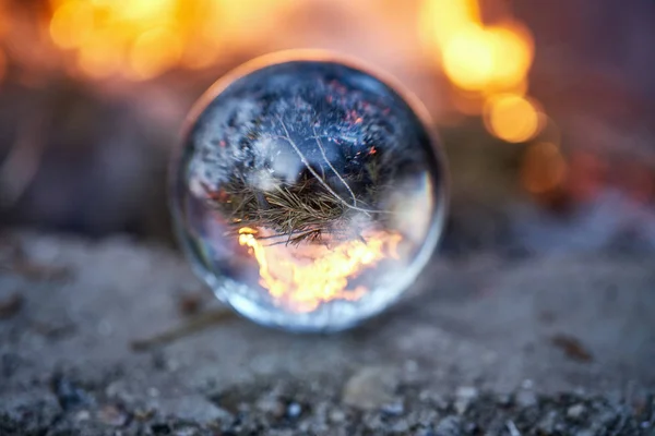 Vue à l'envers à travers la boule de verre sur le feu de camp brouillé dans la forêt — Photo