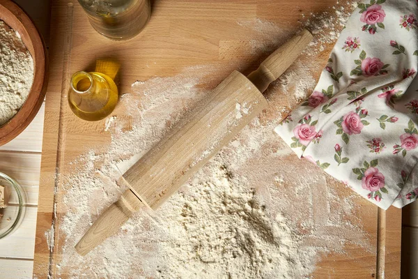 Ingredients for dough on pastry board with flour and rolling pin on table