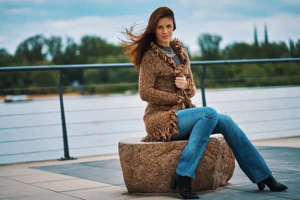 Красивая молодая женщина позирует на скамейке на набережной у реки — стоковое фото