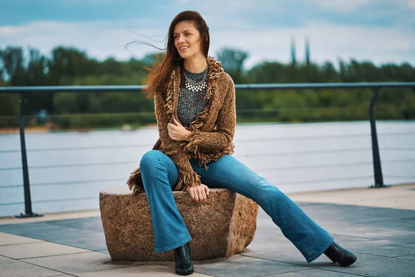 Красивая молодая женщина позирует на скамейке на набережной у реки — стоковое фото