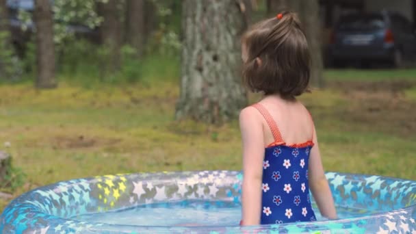 Pequena menina bonito banhos na piscina no jardim no dia de verão — Vídeo de Stock