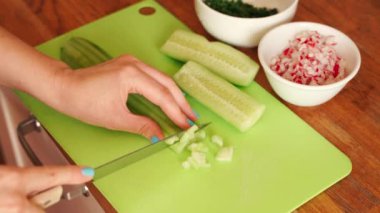 Kadın ahşap masaüzerinde mutfakta taze salatalık dilimleme olduğunu
