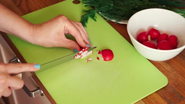 Donna sta affettando ravanello fresco in cucina sul tavolo di legno — Video Stock