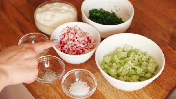 Woman prepares ingredients for cold beetroot soup on wooden table — Stock Video