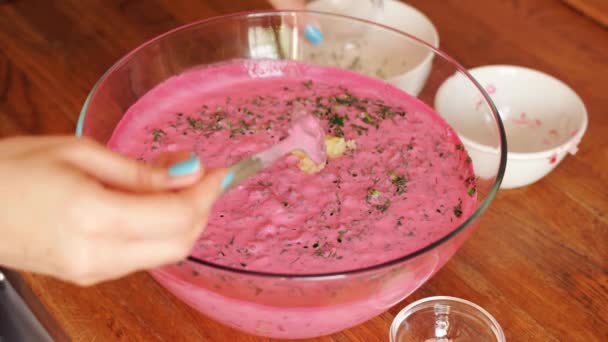 Mujer prepara sopa de remolacha fría en un tazón de vidrio sobre una mesa de madera — Vídeos de Stock