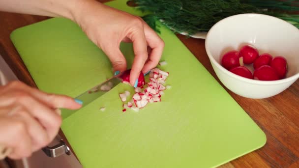 Γυναίκα κόβει φρέσκο ραπανάκι στην κουζίνα σε ξύλινο τραπέζι — Αρχείο Βίντεο