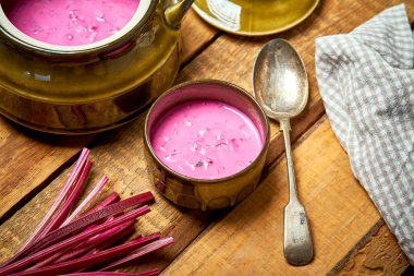 Rustik ahşap masa üzerinde soğuk pancar çorbası ve kaşık ile eski vazo