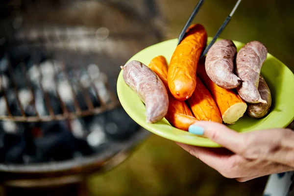 Salsicha suculenta na grelha quente com pinças durante o churrasco de verão — Fotografia de Stock