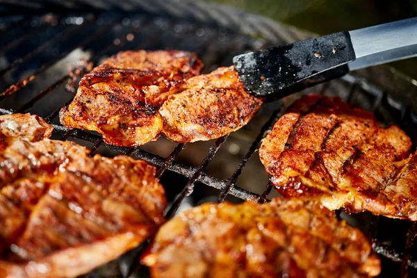 Bifes de carne suculentos na grelha quente com chama no churrasco no jardim — Fotografia de Stock