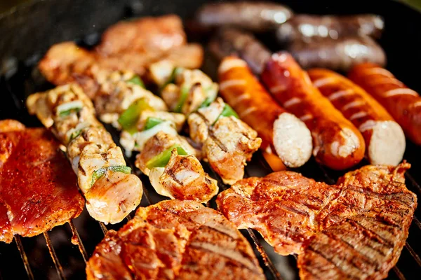 Different types of juicy meats on hot coals on grill in garden — Stock Photo, Image