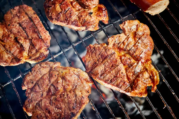 Filetes de carne jugosa en la parrilla con llama en la barbacoa en el jardín —  Fotos de Stock