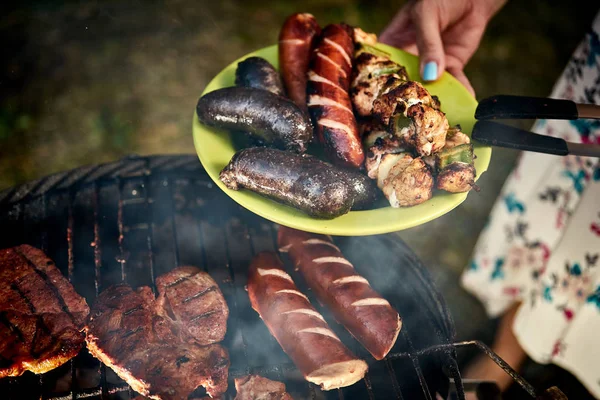 Salsicce succose direttamente dalla griglia sul piatto verde dal barbecue caldo — Foto Stock