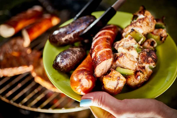 Sappige worstjes rechtstreeks van Grill op groene plaat van hete barbecue — Stockfoto
