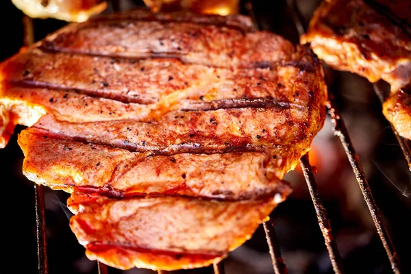 Bifes de carne suculentos na grelha com chama no churrasco no jardim — Fotografia de Stock