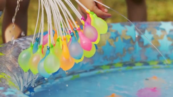 Primer plano de globos de agua de colores llenos de agua en el día de verano — Vídeo de stock