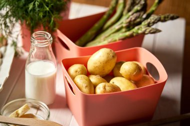 Beyaz mutfak masasında taze kuşkonus patates ve Frenk soğanı