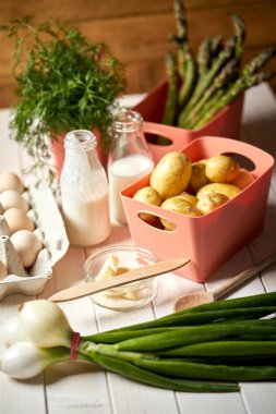 Beyaz mutfak masasında taze kuşkonus patates ve yumurta