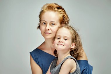 Güzel küçük kızı ile anne poz içinde stüdyo üzerinde gri arka plan