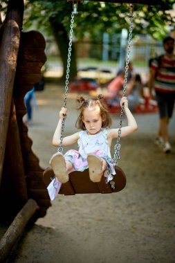 Oyun üzerinde dalgın yüz ile salıncak üzerinde küçük güzel üzgün kız