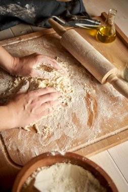 Kadın ahşap masada un ve haddeleme pin ile pasta tahtası üzerinde hamur hazırlar