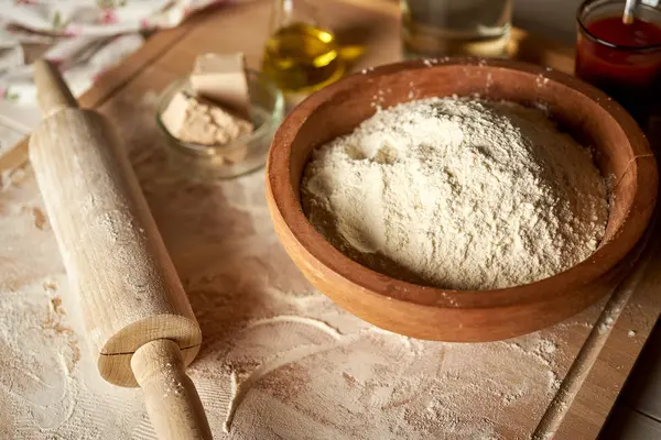 Ingredients for dough on pastry board with flour and rolling pin on  table