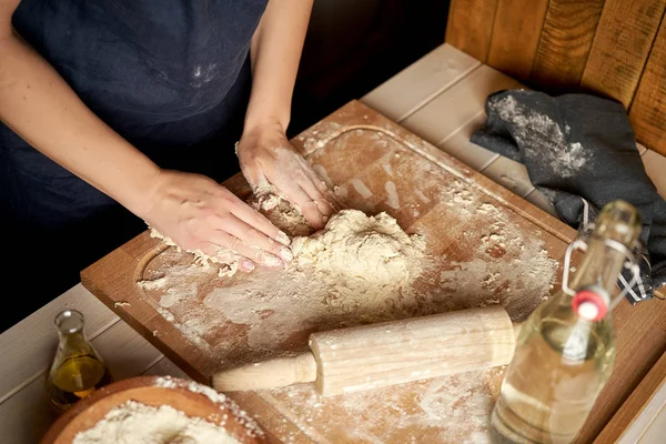 Kadın ahşap masada un ve haddeleme pin ile pasta tahtası üzerinde hamur hazırlar — Stok fotoğraf
