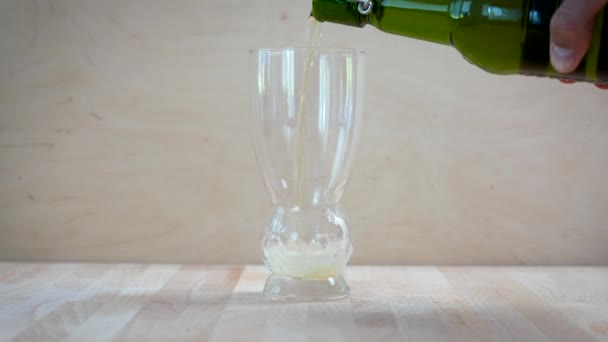 Mans hand houdt een fles en giet bier in een glas — Stockvideo