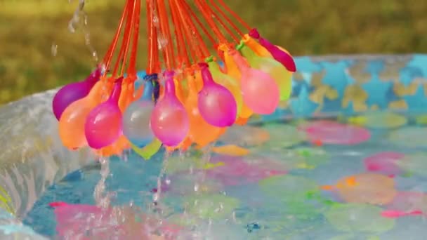 Primer plano de globos de agua de colores llenos de agua en el día de verano — Vídeo de stock