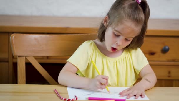 Kleines Mädchen im gelben Kleid mit Buntstiften zeichnet auf Papier — Stockvideo