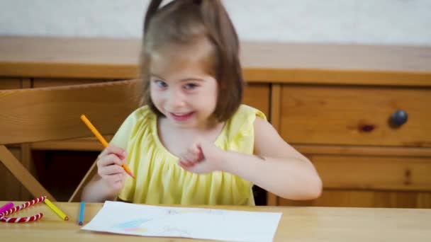 Meisje in een gele jurk met krijtjes trekt op papier — Stockvideo